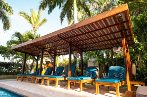 a group of chairs under a pergola next to a pool at Casa Verano Beach Hotel - Adults Only in Santa Marta