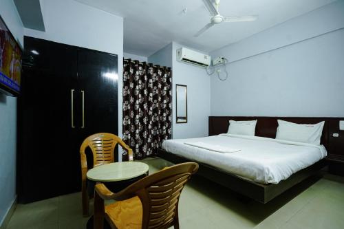 a bedroom with a bed and a table and chairs at Hotel Golden Rooms in Tirupati