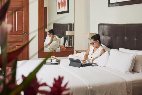 a woman sitting on a bed using a laptop at El Dorado Classic Hotel in Iquitos
