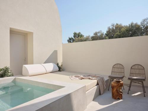 a patio with a swimming pool and two chairs at Heyday Luxury Suites in Perissa