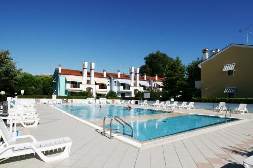 una gran piscina con sillas blancas y un edificio en Le Briccole, en Cavallino-Treporti