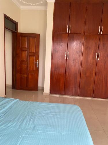 a bedroom with wooden cabinets and a blue bed at Kyanja 2 BDRM Apartment in Buwate