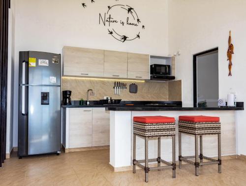 a kitchen with a refrigerator and a counter with stools at Casas Campestres Los Miradores de Fruworld in Carmen de Apicalá