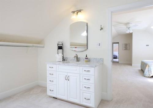 Un baño blanco con lavabo y espejo. en Sunset Point Pool House Close to Duke University, en Durham