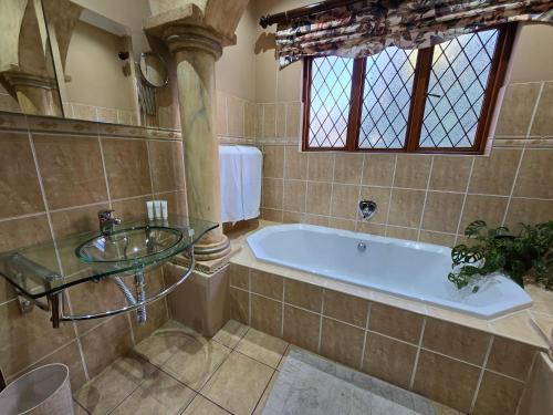 a bathroom with a tub and a glass sink at President's Place in Parys