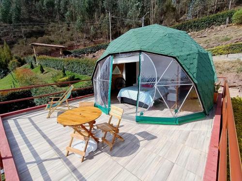 a green tent with a table and chairs on a deck at Glamping El Porvenir in La Unión
