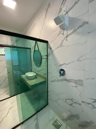 a bathroom with a glass shower with a sink at Pousada Cigarras da Serra in Serra do Cipo