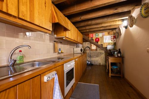 a kitchen with wooden cabinets and a sink at Casa da Aldeia “Póvoa Dão” in Povoa Dao