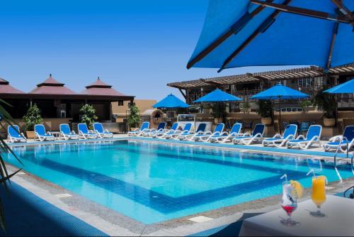 a pool with chairs, tables, and umbrellas at Safir Hotel Cairo in Cairo