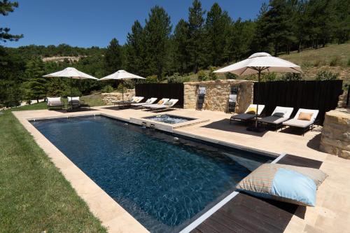 une piscine avec chaises et parasols dans une cour dans l'établissement Domaine de la Lisière, à Sault