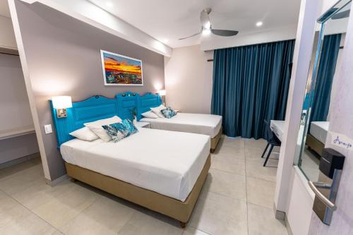 a hotel room with two beds and a tv at Casa Verano Beach Hotel - Adults Only in Santa Marta