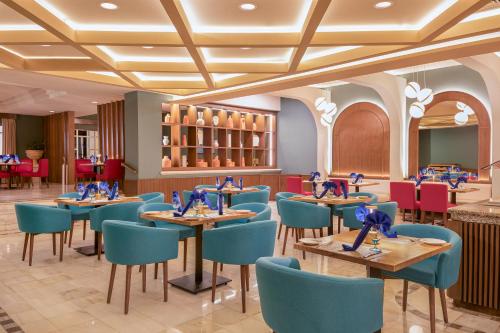 a dining room with tables and blue chairs at GR Solaris Cancun - All Inclusive in Cancún