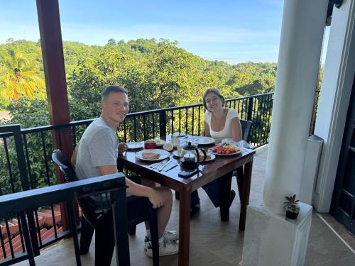 a man and woman sitting at a table on a balcony at Hideaway Homestay kandy in Haloluwa