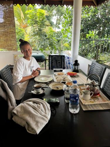 a woman standing in front of a table with food at Hideaway Homestay kandy in Haloluwa