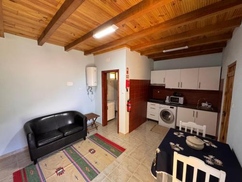 a living room with a black leather couch and a kitchen at Casa do Batista in Seixal