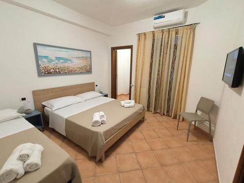 a hotel room with two beds and a chair at Le perle 2 di Naxos in Giardini Naxos