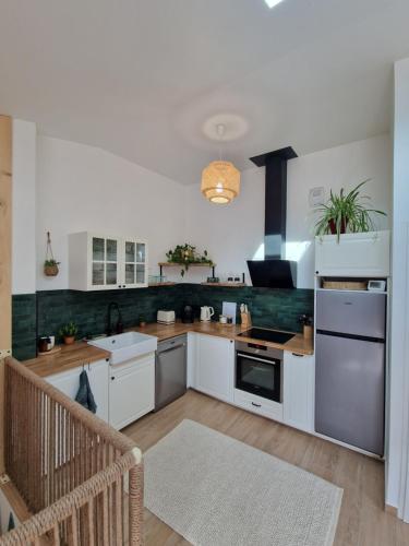 une cuisine avec des armoires blanches et un four à plaques de cuisson dans l'établissement Boêmia - Appartement cosy au coeur des montagnes, à Saint-Jean-de-Maurienne