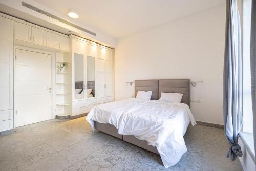 a white bedroom with a large bed with white sheets at אחוזת קסם in Yerushalayim
