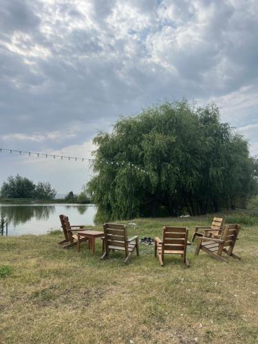 a group of wooden benches sitting next to a lake at Chadir yurd glamp in İsmayıllı