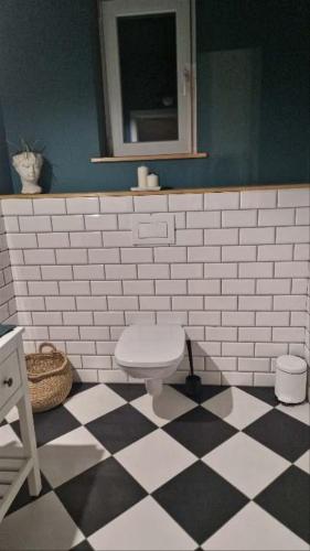 a bathroom with a toilet on a checkered floor at Siedlisko na Agatowej w Rudnie in Rudno