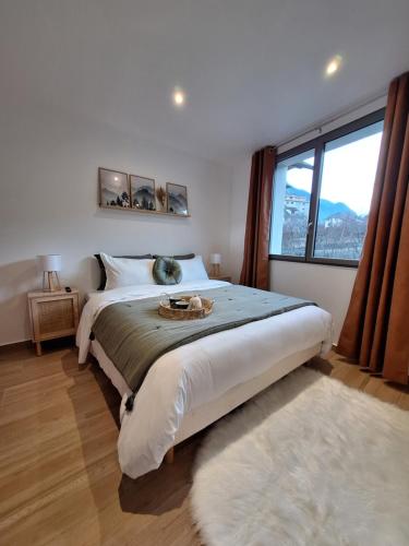 une chambre avec un grand lit et une grande fenêtre dans l'établissement Boêmia - Appartement cosy au coeur des montagnes, à Saint-Jean-de-Maurienne