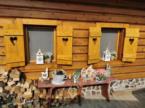 a wooden wall with windows and a table with flowers at Chalupka u macka in Párnica