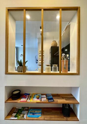 a shelf with books on it in front of a mirror at Appartement de Charme - Le Large in La Tente-Verte