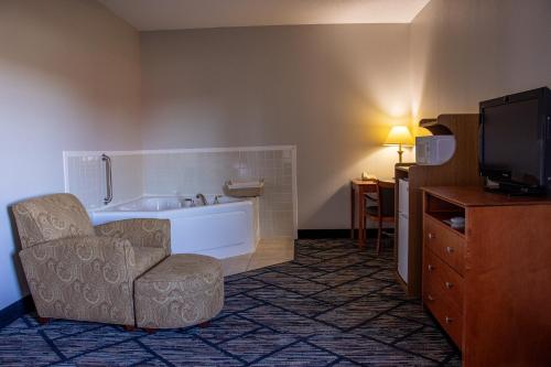 a bathroom with a tub and a chair and a television at Belva Deer Inn in Sigourney