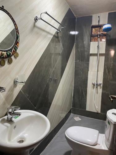 ein Badezimmer mit Waschbecken, Toilette und Spiegel in der Unterkunft New Kitisuru Apartment in Nairobi