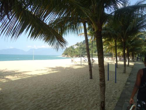 a beach with palm trees and the ocean at Apartamento Aconchegante Porto Real Resort Mangaratiba in Mangaratiba