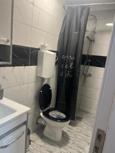 a bathroom with a toilet with a black shower curtain at Vukmanović apartmani in Kikinda