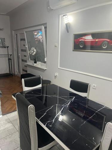 a dining room with a glass table and a red car on the wall at Vukmanović apartmani in Kikinda