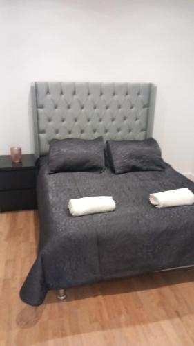 - un grand lit avec une couverture et des oreillers noirs dans l'établissement PARIS et CDG, à Livry-Gargan