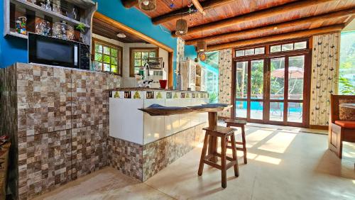 a kitchen with a counter and a tv in a room at Manacá Suítes Prumirim in Ubatuba