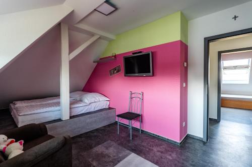 a room with a pink wall with a bed and a tv at Mein alter Bauernhof Strassburgerhof in Welling