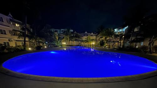 a large blue swimming pool at night at Le Dattier - Three bedroom apartment - Coquillage in Flic-en-Flac