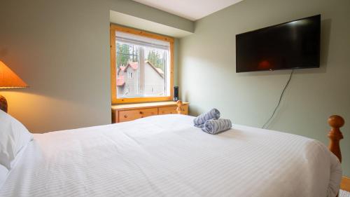 a bedroom with a white bed and a window at Stone Creek Chalet by Fernie Lodging Company in Fernie