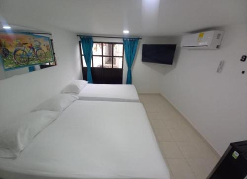 a bedroom with a white bed and a window at Hostal Doña Betty 2 in Cartagena de Indias