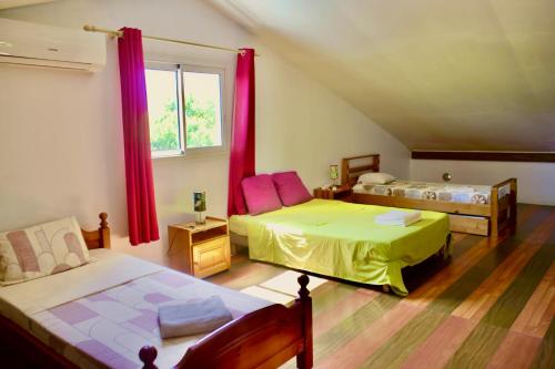 a bedroom with two beds and a window with red curtains at La Kaz Isle Bourbon in Saint-Pierre