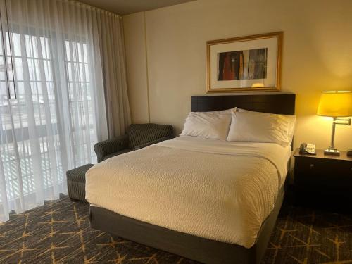 a hotel room with a bed and a chair at Holiday Inn & Suites Springfield-I-44 by IHG in Springfield