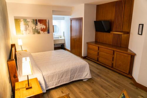 a bedroom with a bed and a flat screen tv at Hotel Suites El Paseo in Ciudad Juárez