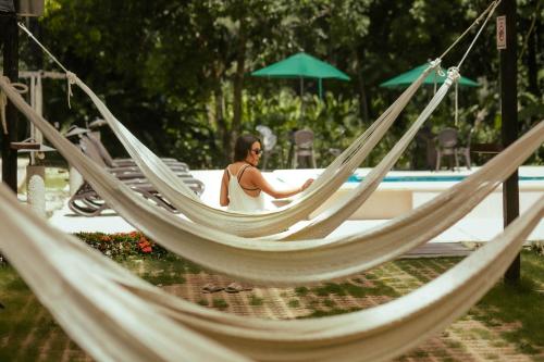 a woman sitting in a hammock near a pool at Cabañas Kin Balam Palenque in Palenque