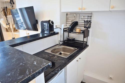 une cuisine avec un évier et un plan de travail noir dans l'établissement Grand T2 Élégant à Nation, Paris, à Paris