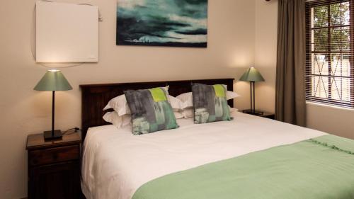 a bedroom with a bed with green and white pillows at 39 On Nile Guest House in Port Elizabeth