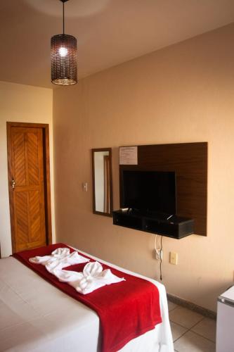 a bedroom with a bed with a red blanket and a flat screen tv at Recanto Pequena Sereia in São Mateus