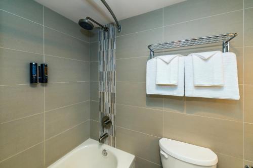 a bathroom with a shower and a toilet and towels at Banff Inn in Banff