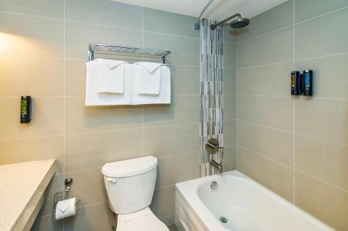 a bathroom with a toilet and a tub and towels at Banff Inn in Banff