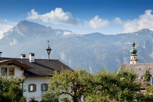 a house with a green turret and mountains in the background at Landhaus Greil in Reith im Alpbachtal