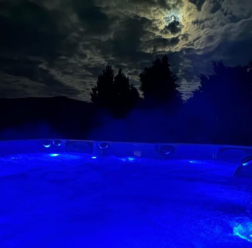 a blue lighted pool at night with a moon at LuxHome by Lake Neusiedl with Jakuzzi in Fertőszentmiklós