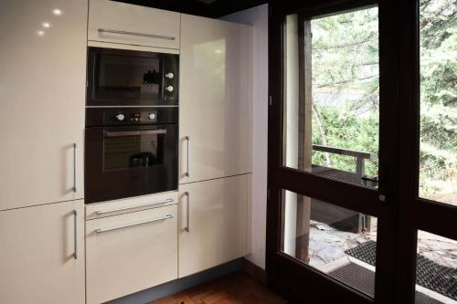 d'une cuisine avec des placards blancs, un four micro-ondes et une fenêtre. dans l'établissement Résidence Chal. Les Chandelles - CHALET Les Chandelles 11 Pers. PIED PISTES MAE-6521, aux Orres